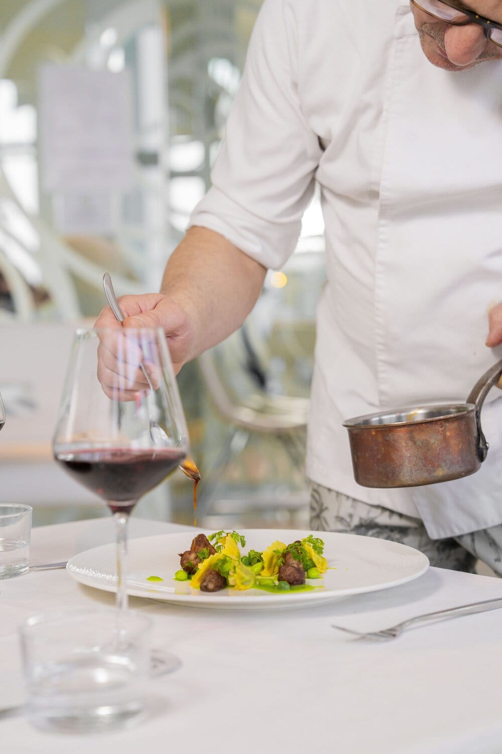 i-SUITE Hotel – Küchenchef serviert ein raffiniert zubereitetes Gourmetgericht.
