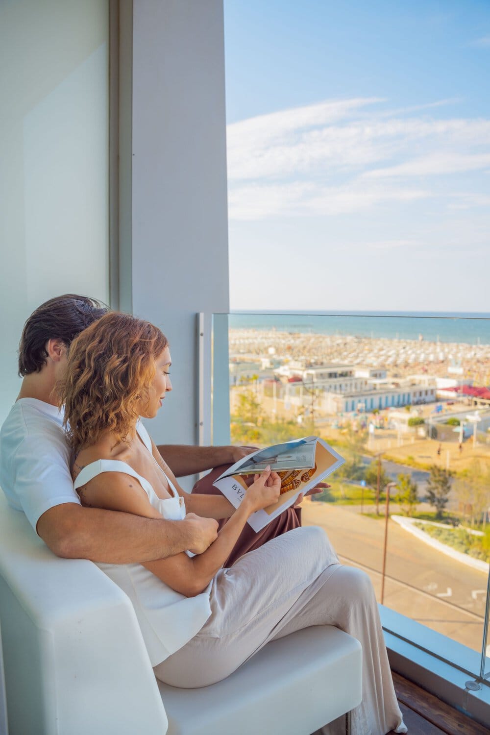 i-SUITE Hotel – Gäste entspannen am Panoramafenster mit Blick auf die Adriaküste.