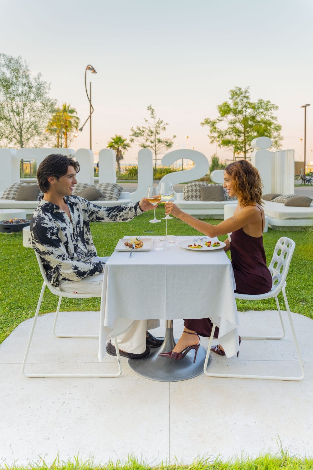 i-SUITE Hotel – Paar genießt ein romantisches Abendessen im Freien bei Sonnenuntergang.